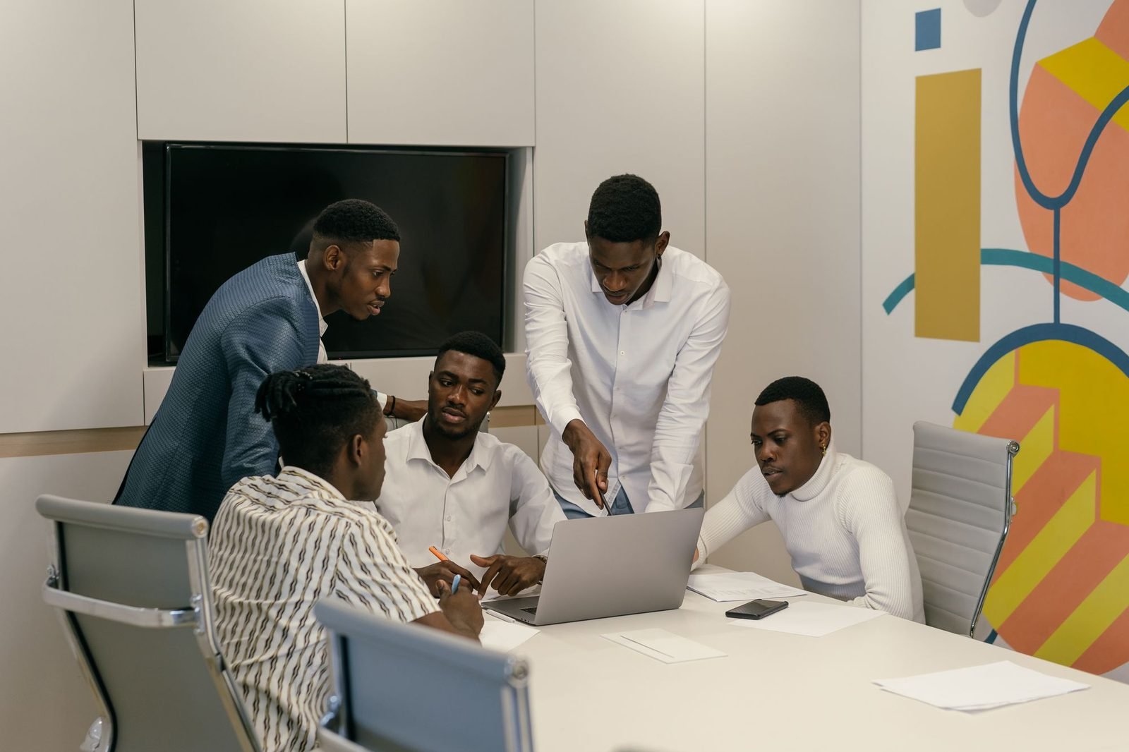A small team of young men planning together around a laptop in a meeting room